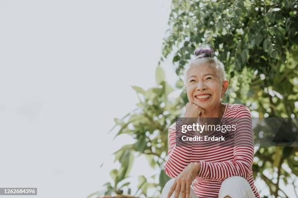 thais senior hipster portret naast de tuin - asian woman fitness stockfoto's en -beelden