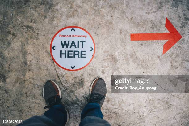 below view of men's foot standing on the marking, waiting for his queue by keep space between people while covid-19 pandemic outbreak. - keep out sign imagens e fotografias de stock