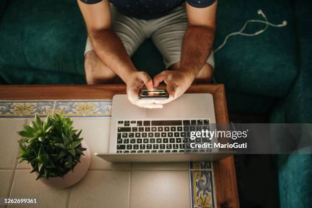 hands holding a smartphone by a laptop computer - password stock pictures, royalty-free photos & images