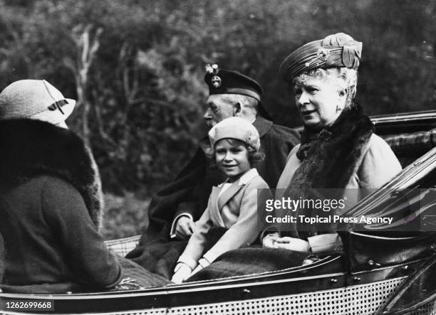 Princess Elizabeth seated between her grandfather King George V and grandmother Queen Mary of Teck as they ride in a carriage back to Balmoral Castle...