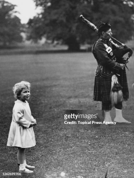 Princess Elizabeth watches members of a pipe band play in the grounds of Glamis Castle near Forfar in Scotland in September 1929.