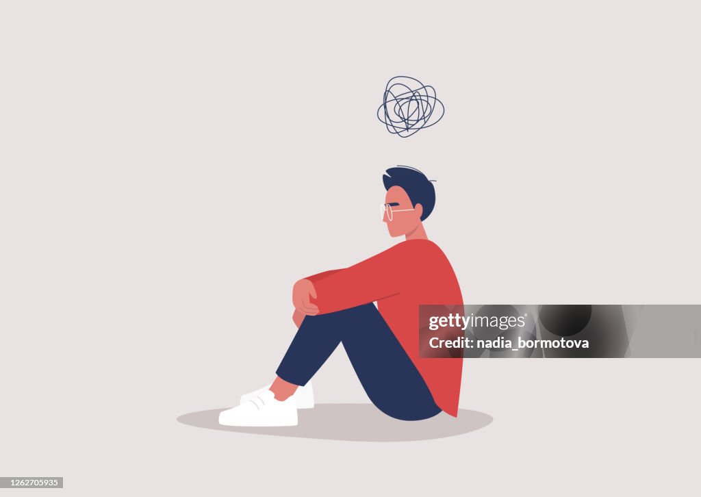 Joven personaje masculino deprimido sentado en el suelo y sosteniendo sus rodillas, un garabato de dibujos animados por encima de su cabeza, problemas de salud mental