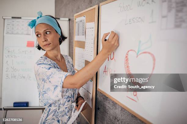 young female teacher writing on whiteboard with marker - teaching english stock pictures, royalty-free photos & images