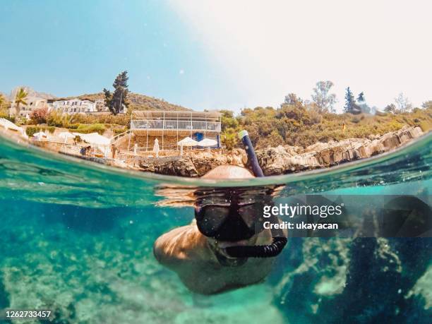 schnorcheln junger mann im türkisfarbenen meer - schnorchel stock-fotos und bilder
