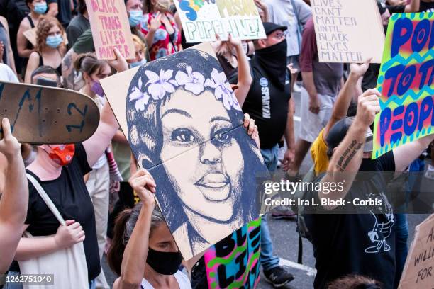 July 26: A protester wearing a mask holds a picture of Breonna Taylor as they walk past Grand Central Station in New York in support of Black Women....