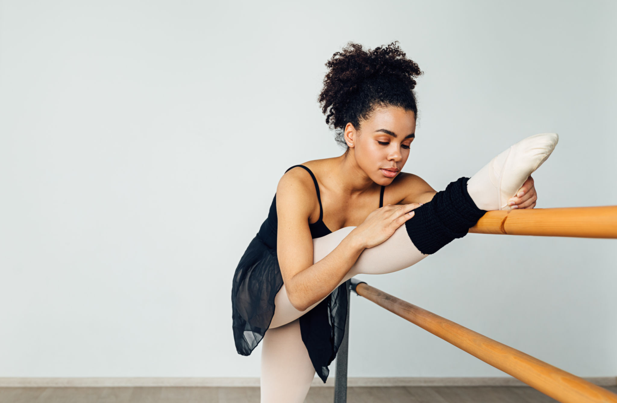 Female ballet dancer stretching her leg. Young woman preparing for a ballet class in a studio. Female ballet dancer stretching her leg. Young woman preparing for a ballet class in a studio.