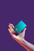 Close up female hand holds levitating template mockup Bank credit card with online service isolated on violet background