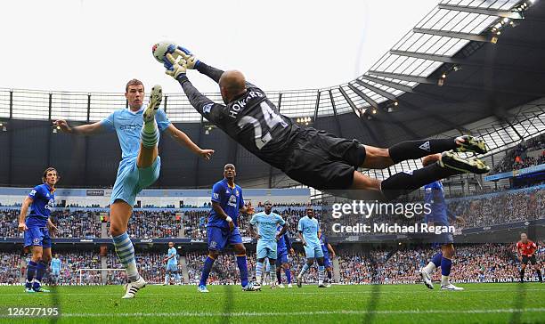 Edin Dzeko of Manchester City challenges as Tim Howard of Everton saves during the Barclays Premier League match between Manchester City and Everton...