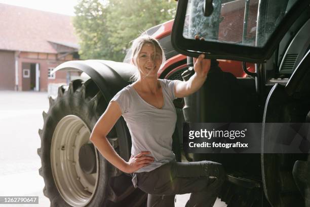 porträt einer bäuerin vor einem traktor - bäuerin stock-fotos und bilder