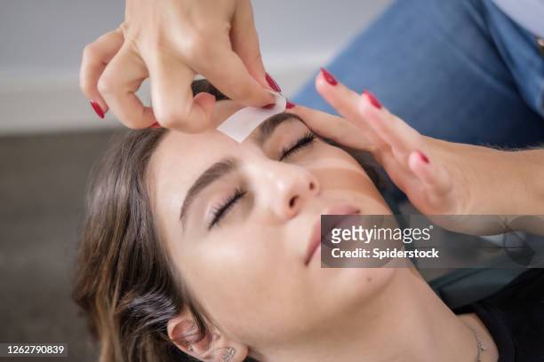 woman receiving eyebrow wax treatment at beauty salon - beautiful armenian women stock pictures, royalty-free photos & images