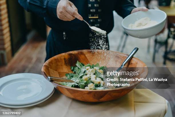 waiter's hands sprinkling parmesan cheese on cesar salad - food dressing stock pictures, royalty-free photos & images