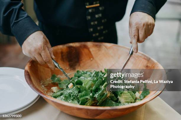 waiter mixing cesar salad in a bowl - cesar salad bildbanksfoton och bilder