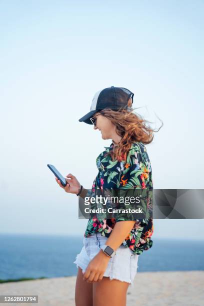 young woman in flower cap and shirt using mobile cell phone. - smartphone strand stock-fotos und bilder