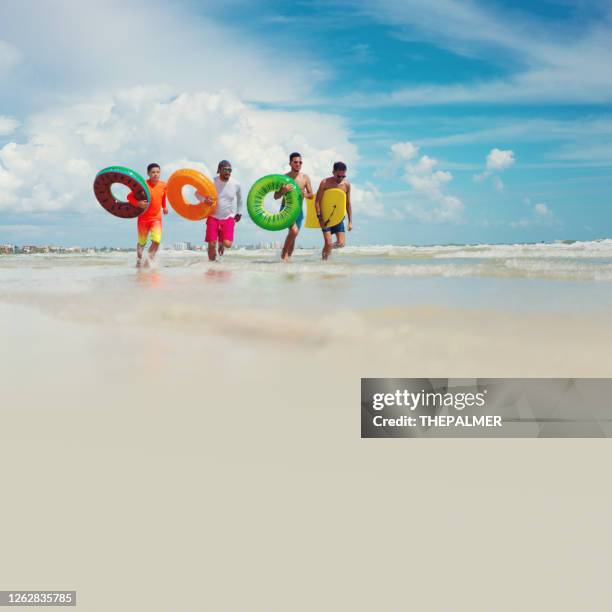 guys with inflatable ring tubes on a beach in fort myers - fort myers stock pictures, royalty-free photos & images