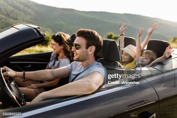 familia despreocupada divirtiéndose durante el viaje por carretera en coche convertible. - convertible fotografías e imágenes de stock