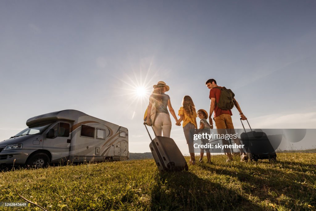 Below view of happy family going on a trip with camp trailer.
