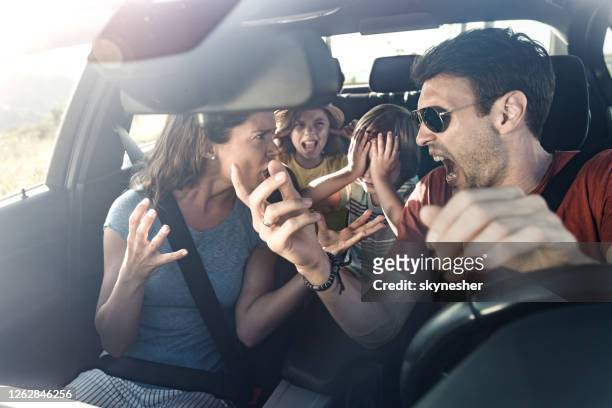 frustrated parents arguing during trip by a car. - fighting stock pictures, royalty-free photos & images
