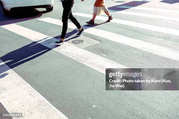 zebra crossing in the sun at taipei street,  two pedestrians walked on it make a long shadow, and a car is leaving. city scenes. - asian women feet stock pictures, royalty-free photos & images