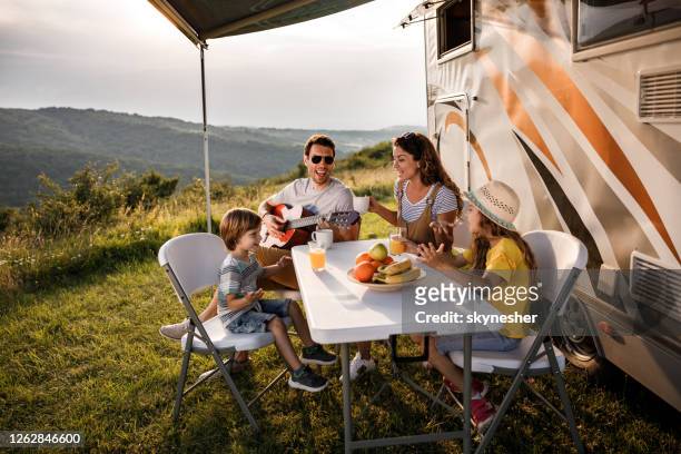 happy family signing during their camping day by the trailer. - trailer imagens e fotografias de stock