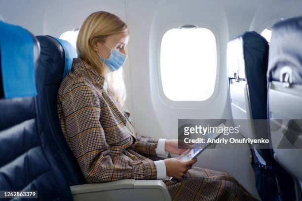 woman wearing mask inside airplane - businesswoman mask stock pictures, royalty-free photos & images