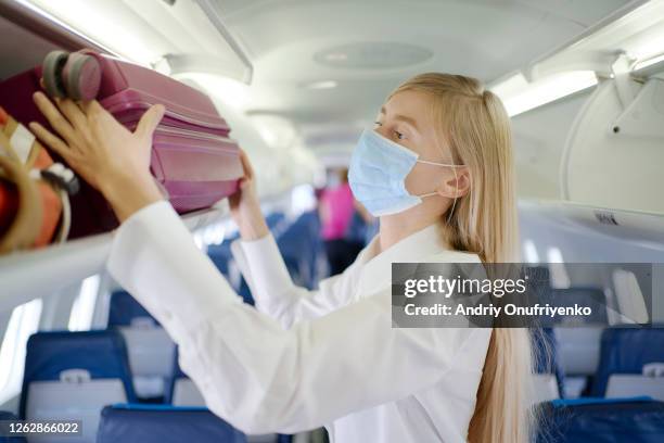 woman wearing mask inside airplane - flu mask stock-fotos und bilder