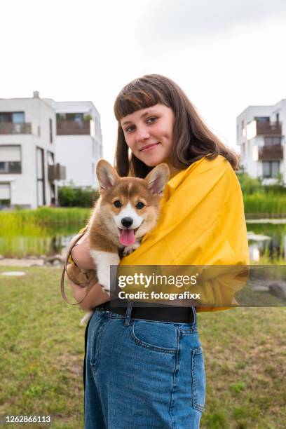 ragazza adolescente carina abbraccia un cucciolo di corgi, sfondo urbano - pembroke welsh corgi puppy foto e immagini stock