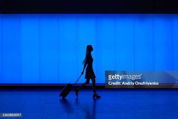 silhouette of walking young woman - vertrekhal stockfoto's en -beelden