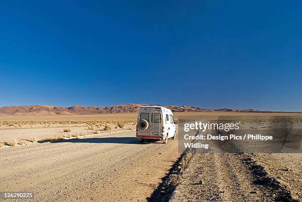 camper van on a desert road on the altiplano of argentina - salinas grandes stockfoto's en -beelden