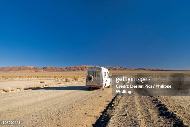 camper van on a desert road on the altiplano of argentina - altiplano imagens e fotografias de stock
