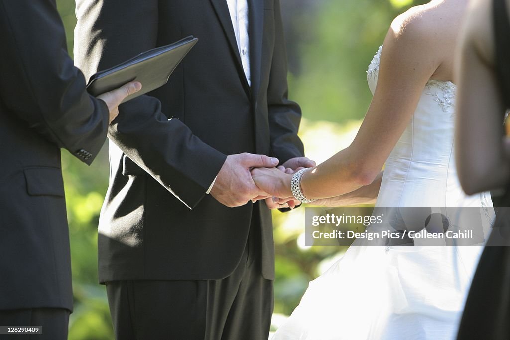 A bride and groom holding hands during their ceremony