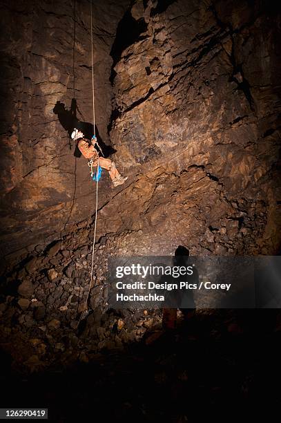 male athlete ascending a rope to exit a cave - höhlenforscher stock-fotos und bilder