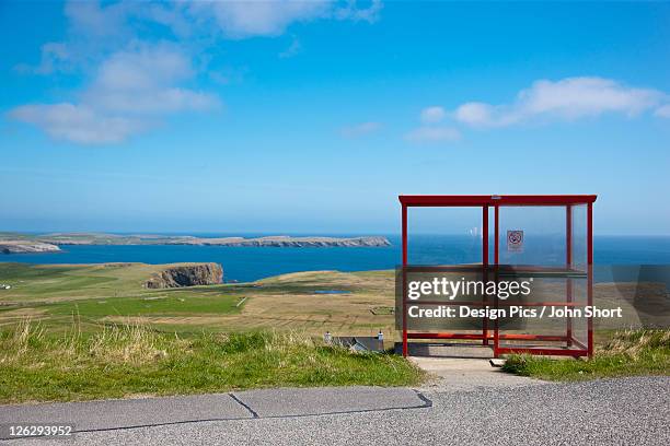 a red shelter on the side of the road - bus shelter stock-fotos und bilder