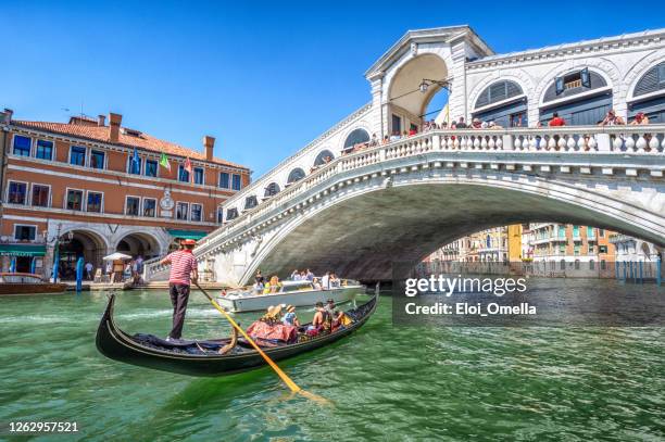 gondel mit touristen auf dem gran canal mit rialtobrücke, venedig - rialto bridge stock-fotos und bilder