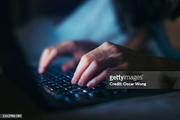 close-up shot of young woman working late with laptop in the dark - computer stockfoto's en -beelden