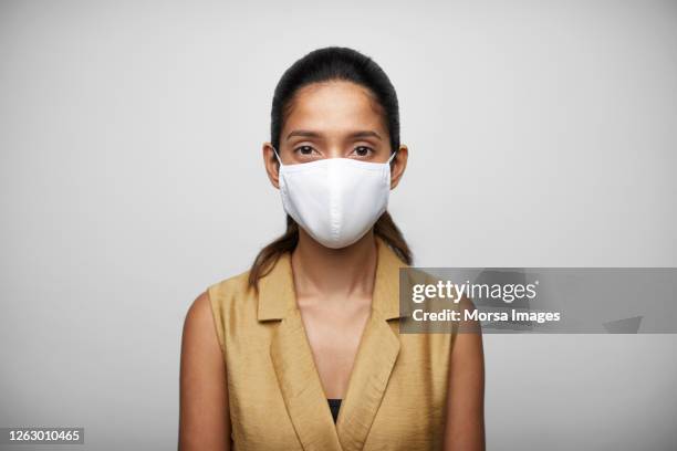 smiling woman against white background wearing n95 face mask. - corporate business covid stock pictures, royalty-free photos & images