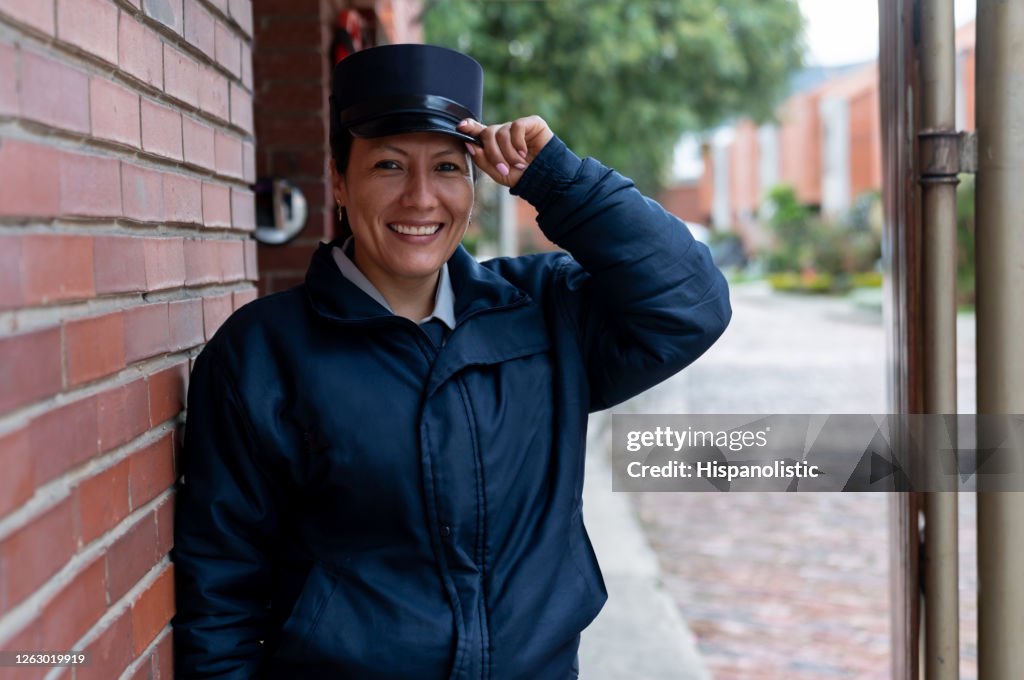 Security guard opening the door of a gated community and greeting with her hat