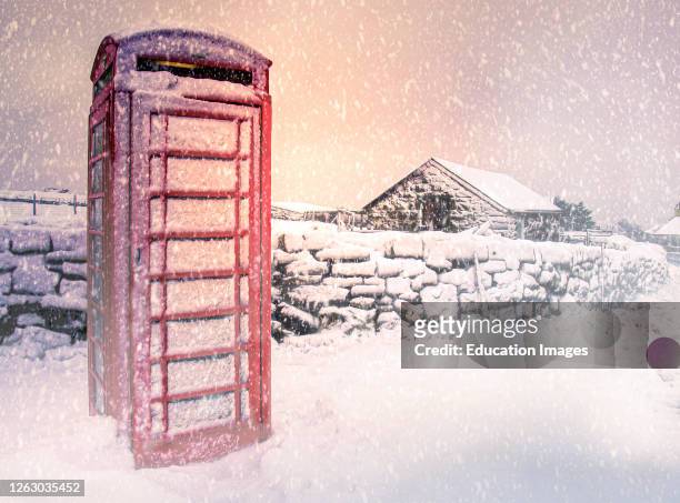 Traditional red telephone box covered in snow, Dartmoor, Devon, UK.