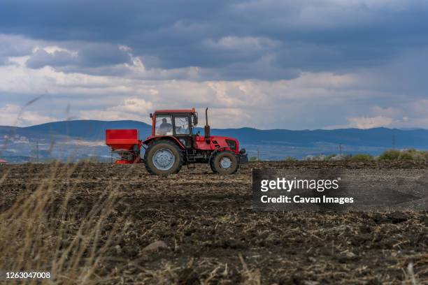 tractor spreading artificial fertilizers at summer - nitro stock-fotos und bilder