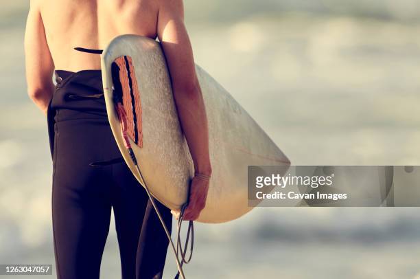 man with board ready to surf - neopren stock-fotos und bilder