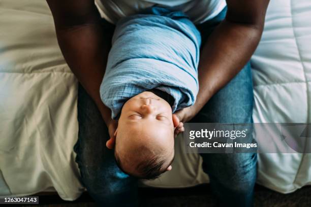 overhead portrait of sleeping baby in dads arms - babydeken stockfoto's en -beelden