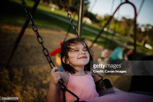 young girl on swing, closing eyes and smiling - parte del corpo animale foto e immagini stock