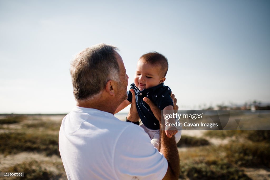Grandfather Holding Grandson While Standing on Beach