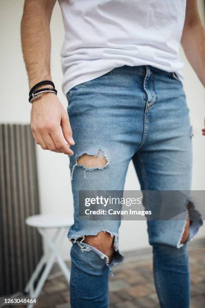 close-up picture of attractive guy with ripped jeans. - zerrissene jeans stock-fotos und bilder