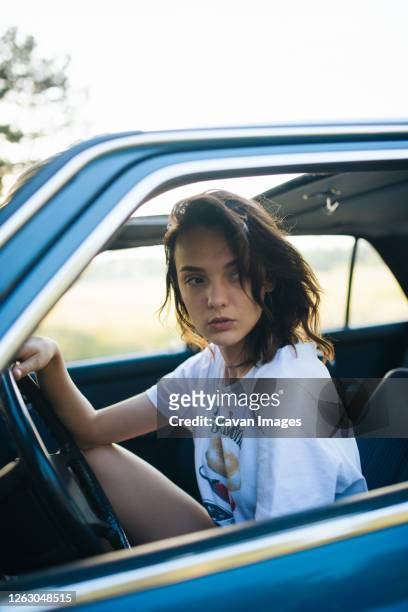 young woman sitting in a parked vintage car. - man driving anxiously stock-fotos und bilder