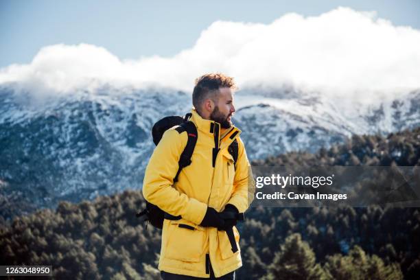 young man with yellow jacket and backpack in the mountains. - madrid snow stock pictures, royalty-free photos & images