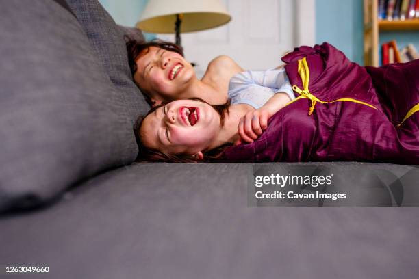 two happy children lay on couch together laughing out loud with joy - columbus ohio house stock pictures, royalty-free photos & images