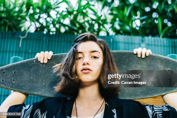 teenage girl with longboard on her back with hawaiian shirt - spain teen face stock-fotos und bilder