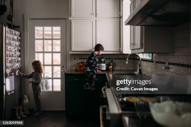 young boy and girl helping in kitchen during breakfast time - coffee capsules stock-fotos und bilder