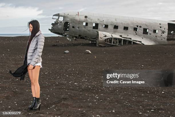 beautiful woman posing at abandoned airplane wreck in iceland - aerospace engineering stock-fotos und bilder