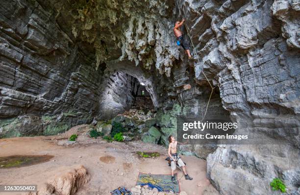 two men climbing at treasure cave in yangshuo, china - zekeren stockfoto's en -beelden